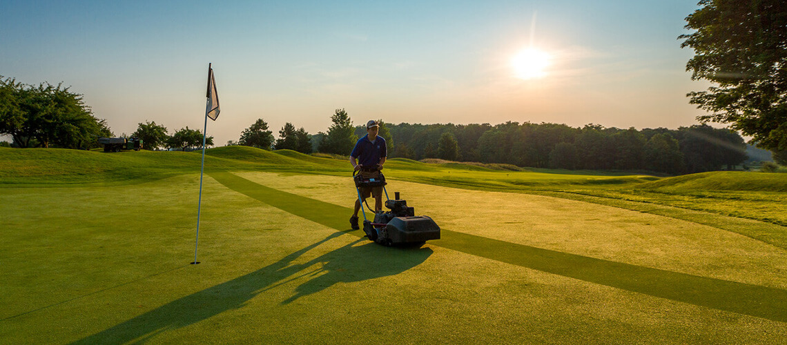 Grand Traverse Resort Crew Member mowing the grass on the green in the early morning