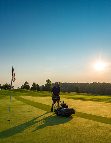 Grand Traverse Resort Crew Member mowing the grass on the green in the early morning